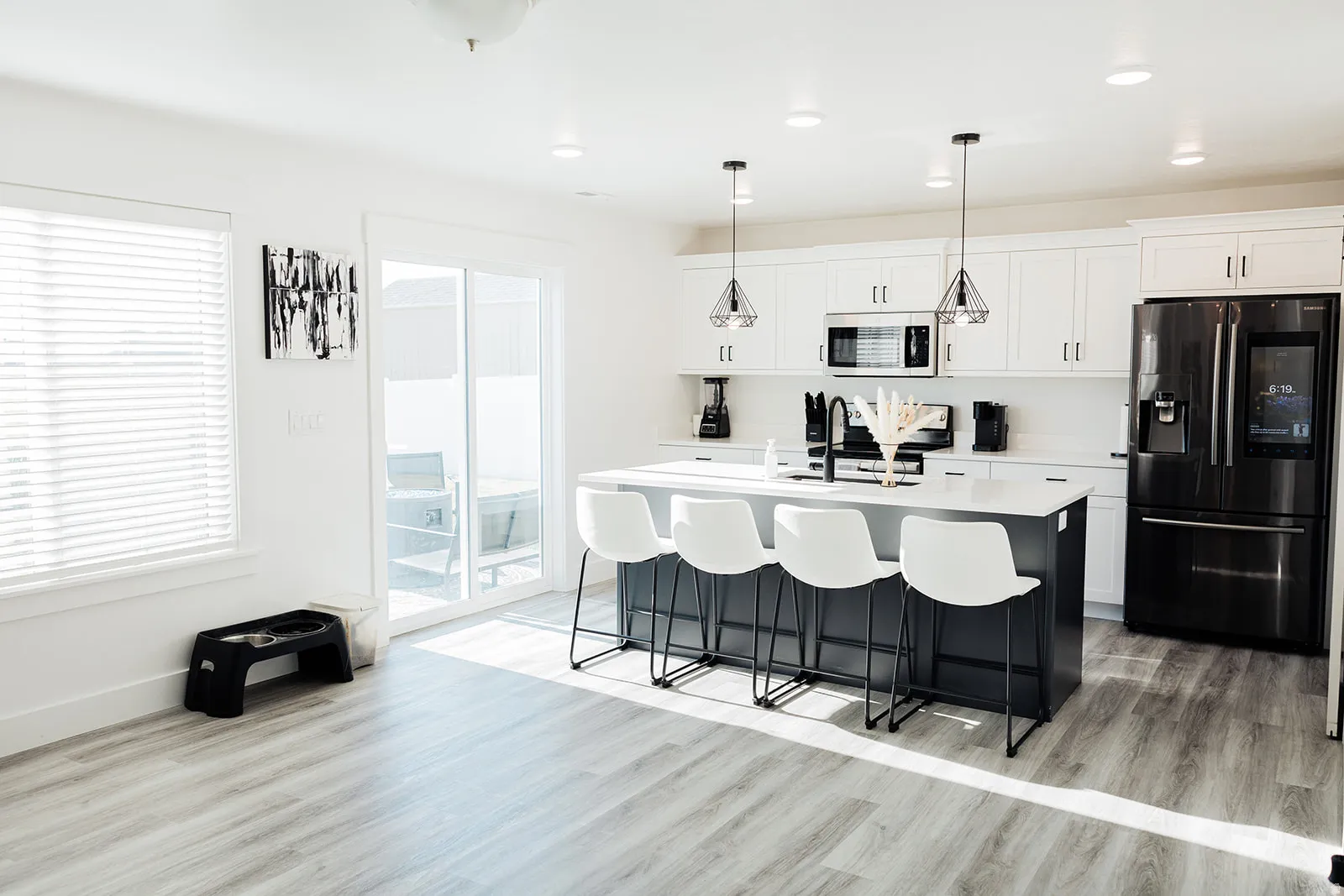 Kitchen featuring a dark-toned island with seating, white shaker-style cabinetry, and stainless steel appliances
