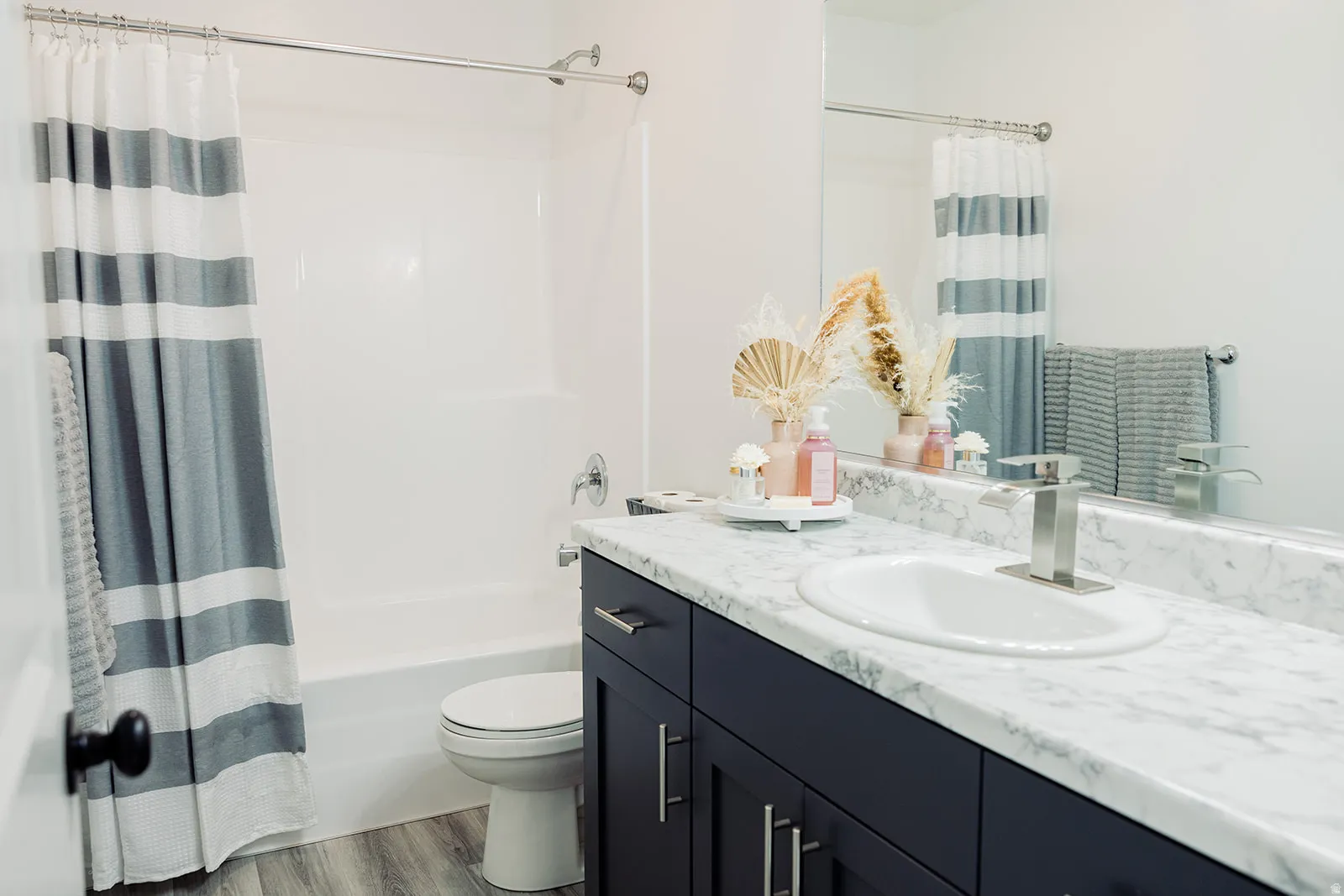 Bathroom featuring a vanity with a white countertop and undermount sink, dark cabinetry, and a chrome faucet