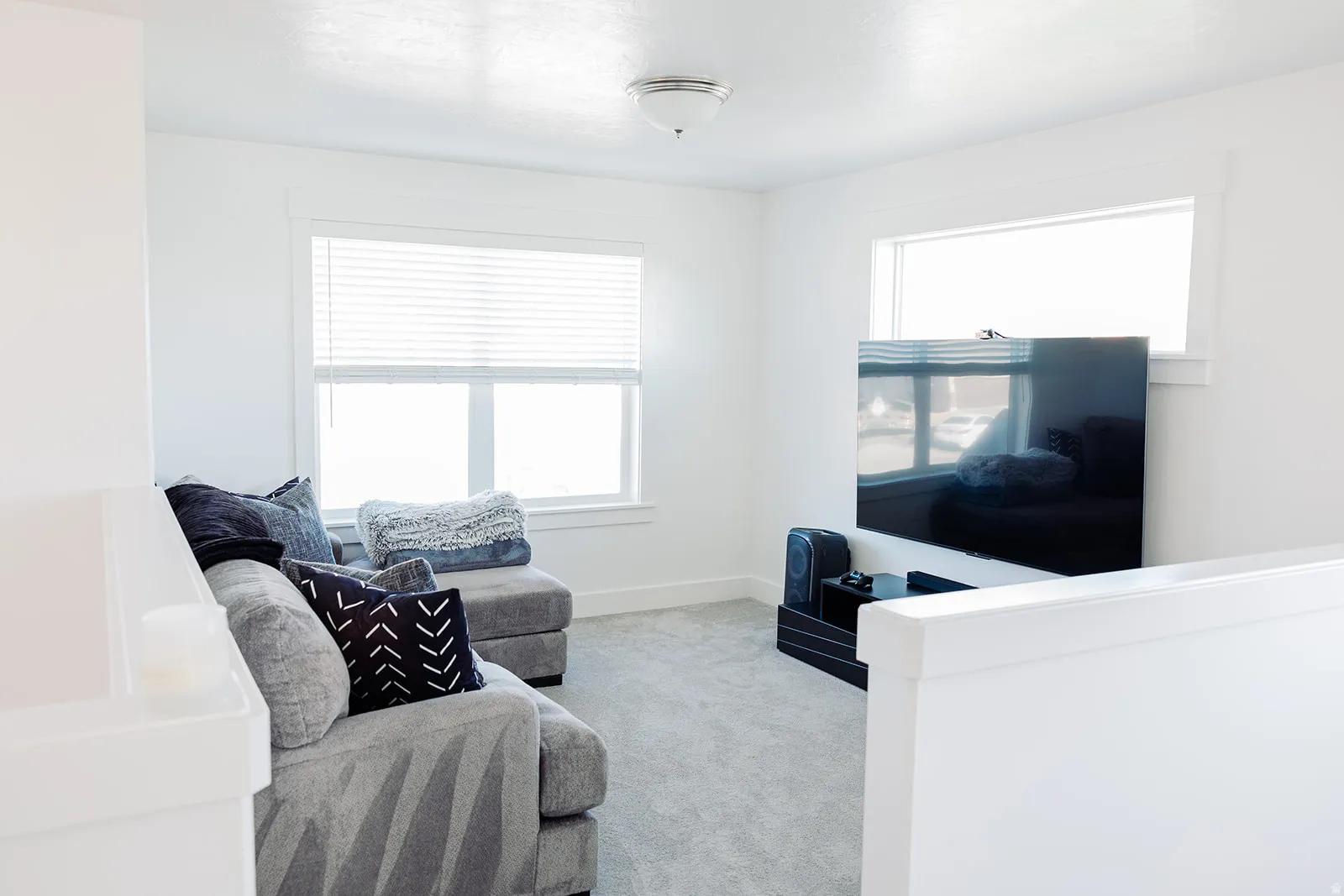 Carpeted room featuring multiple windows with blinds, white walls, and an overhead flush-mount light fixture