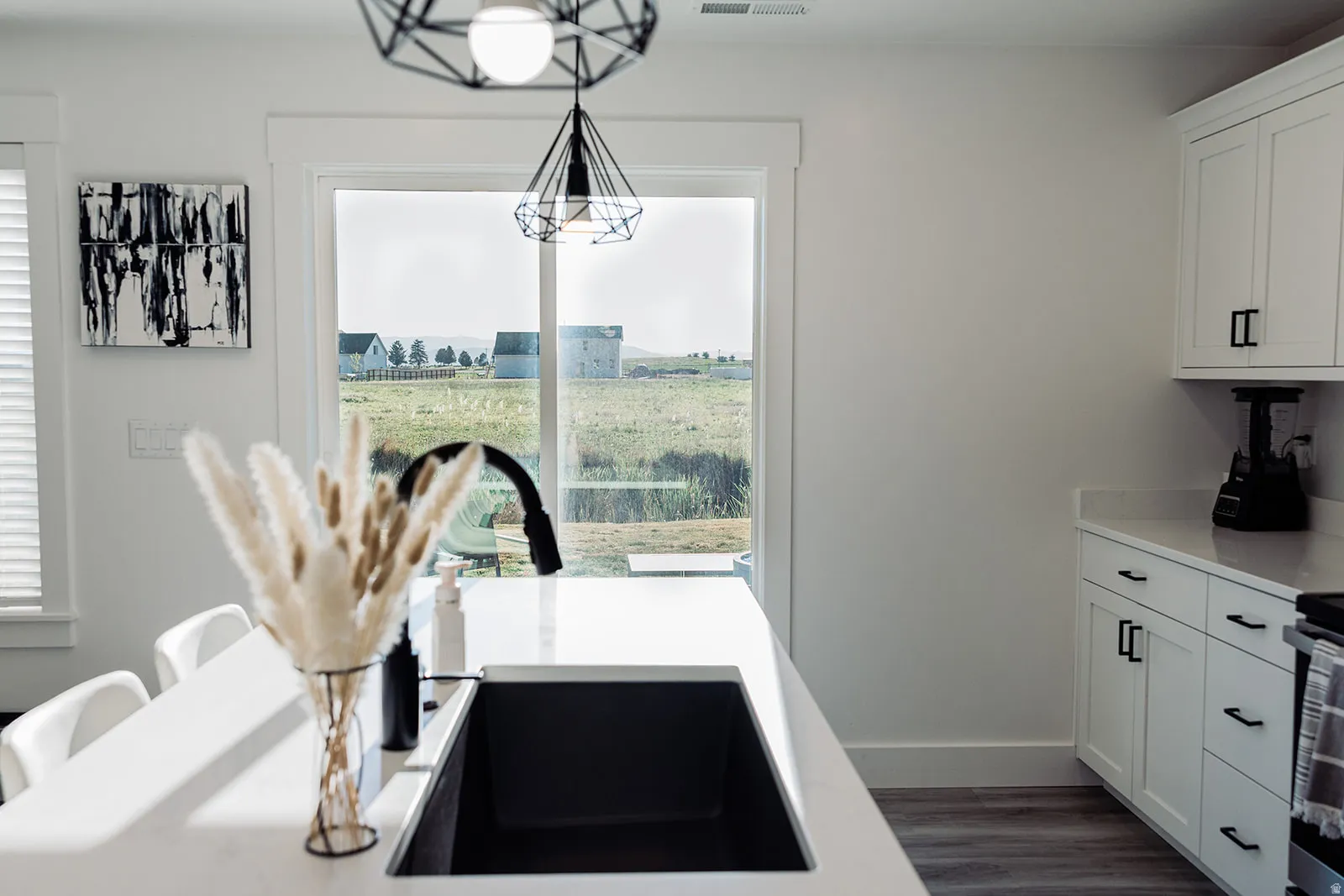 Kitchen featuring white cabinetry with black hardware, white countertops, and wood-finish flooring