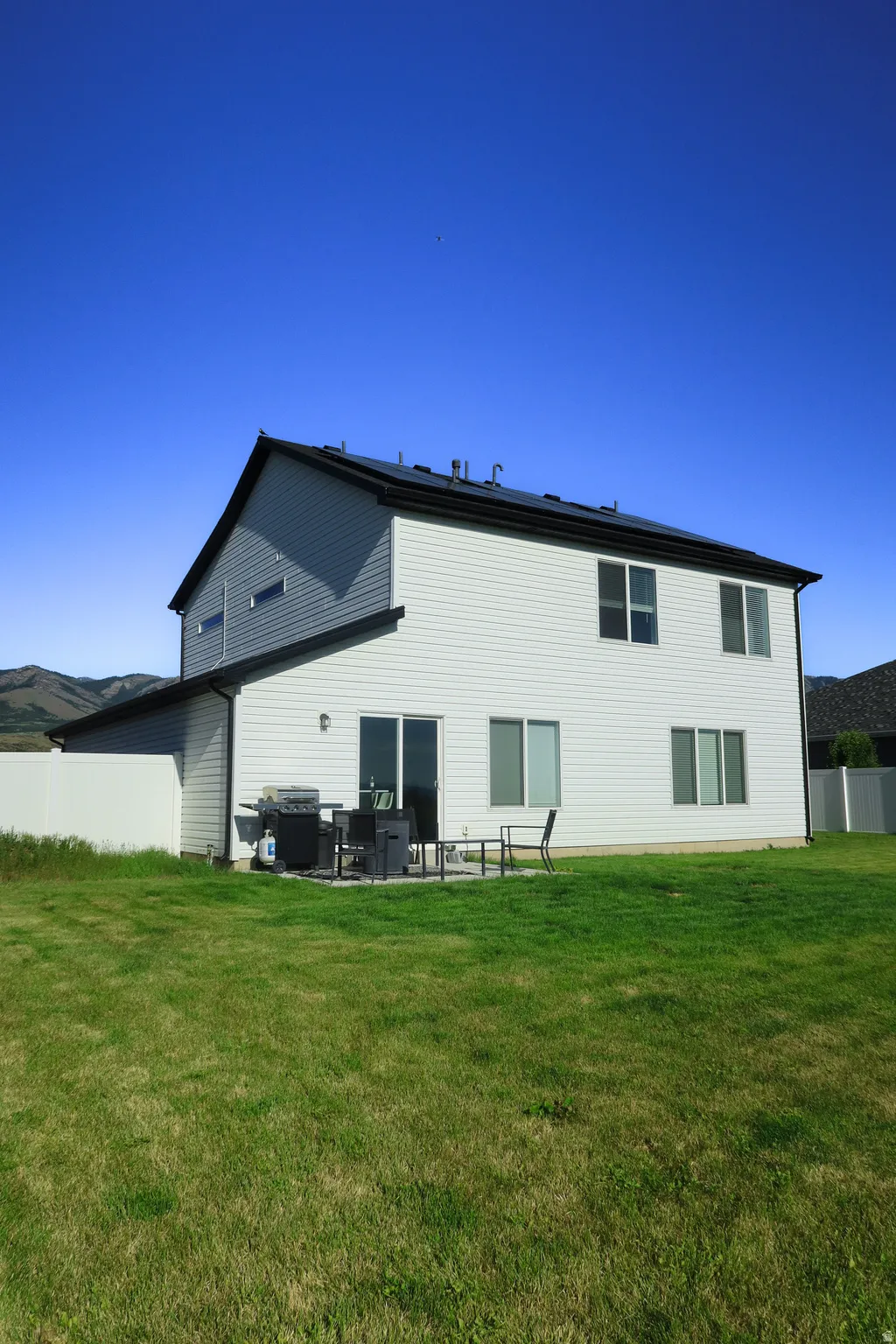 Two-story residence featuring white siding and a black shingle roof