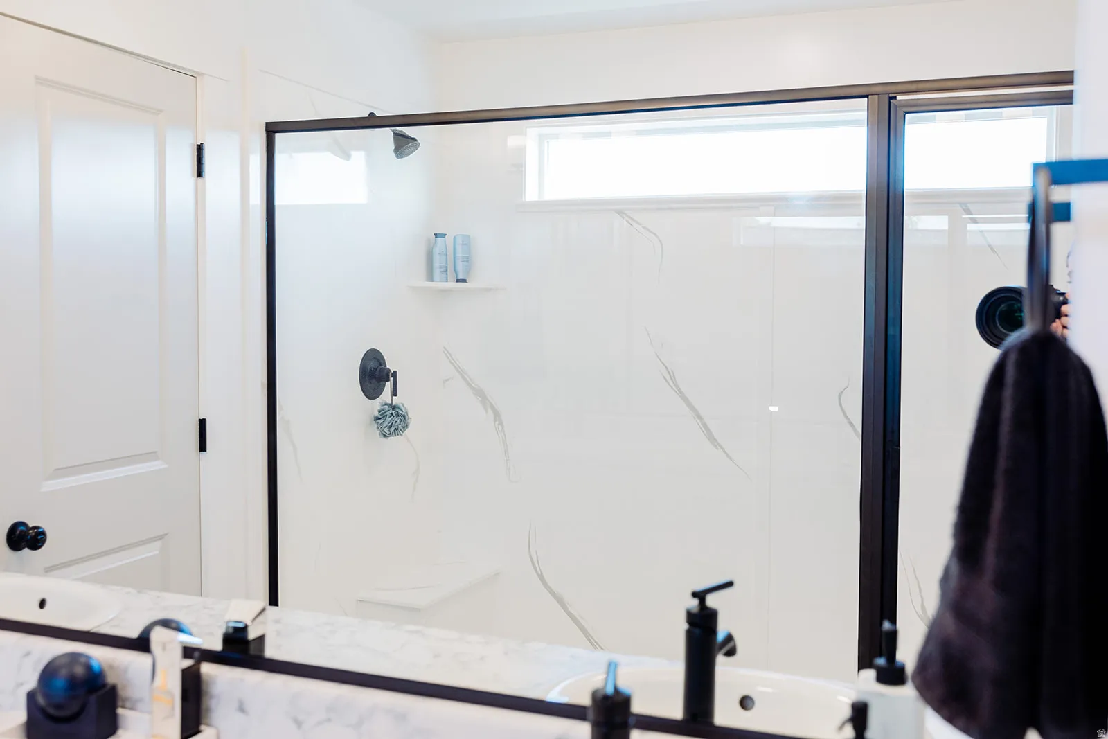 Modern shower enclosure featuring a dark-framed glass panel and white subway tile with subtle grey veining