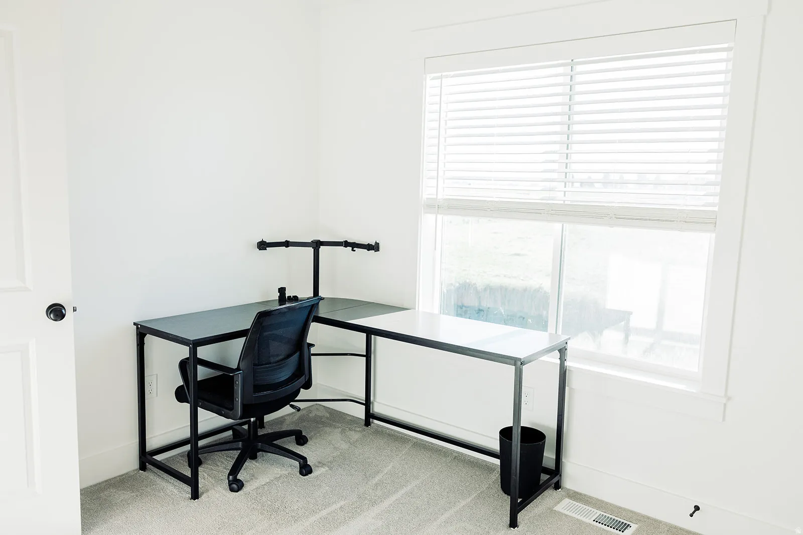 Bright room featuring a large window with horizontal blinds, neutral wall paint, and gray carpet flooring