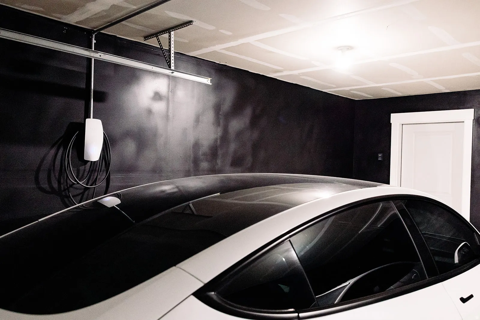 Garage featuring a white EV charger, dark wall finishes.