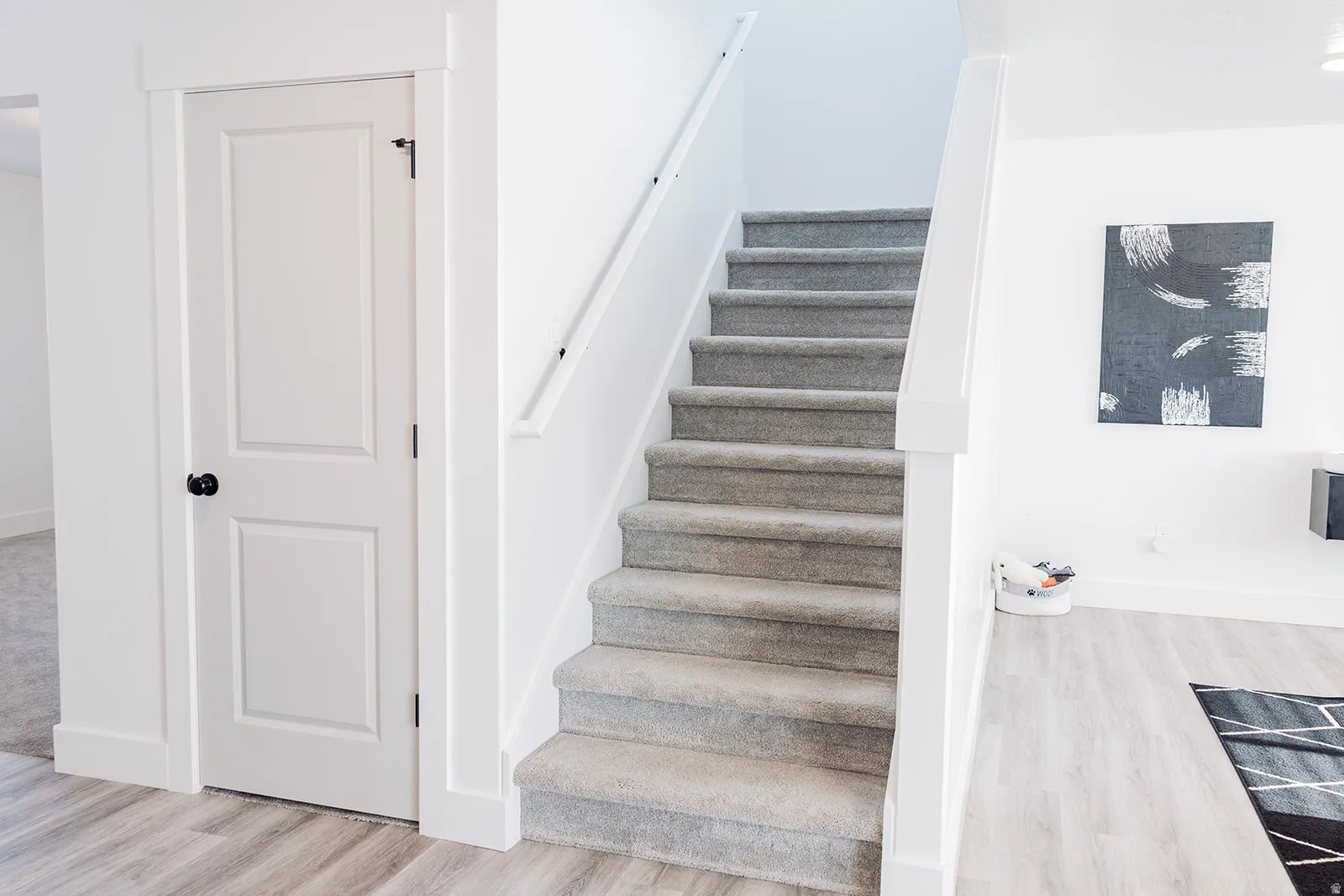 Carpeted staircase with white handrail, leading to an upper level
