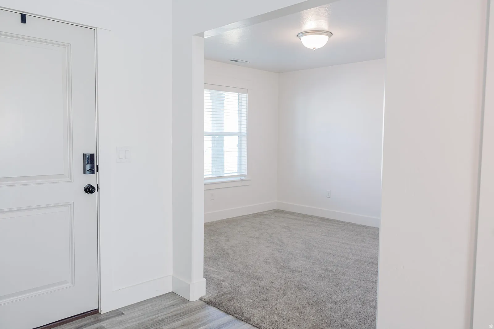 Entryway featuring a paneled door with matte black hardware, wood-finish flooring, and crisp white trim