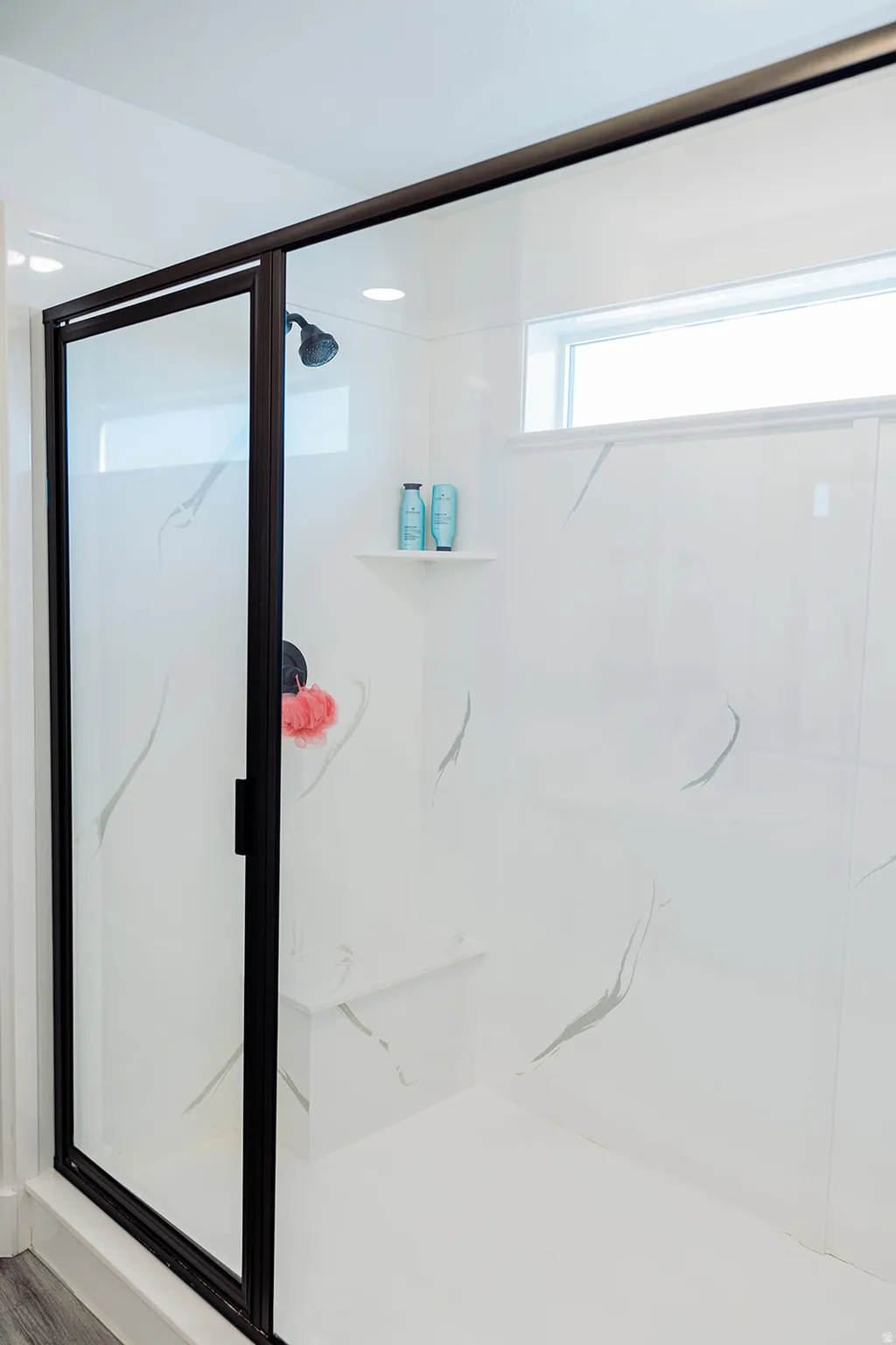Glass-enclosed shower featuring a built-in bench, a fixed shower head, and a transom window