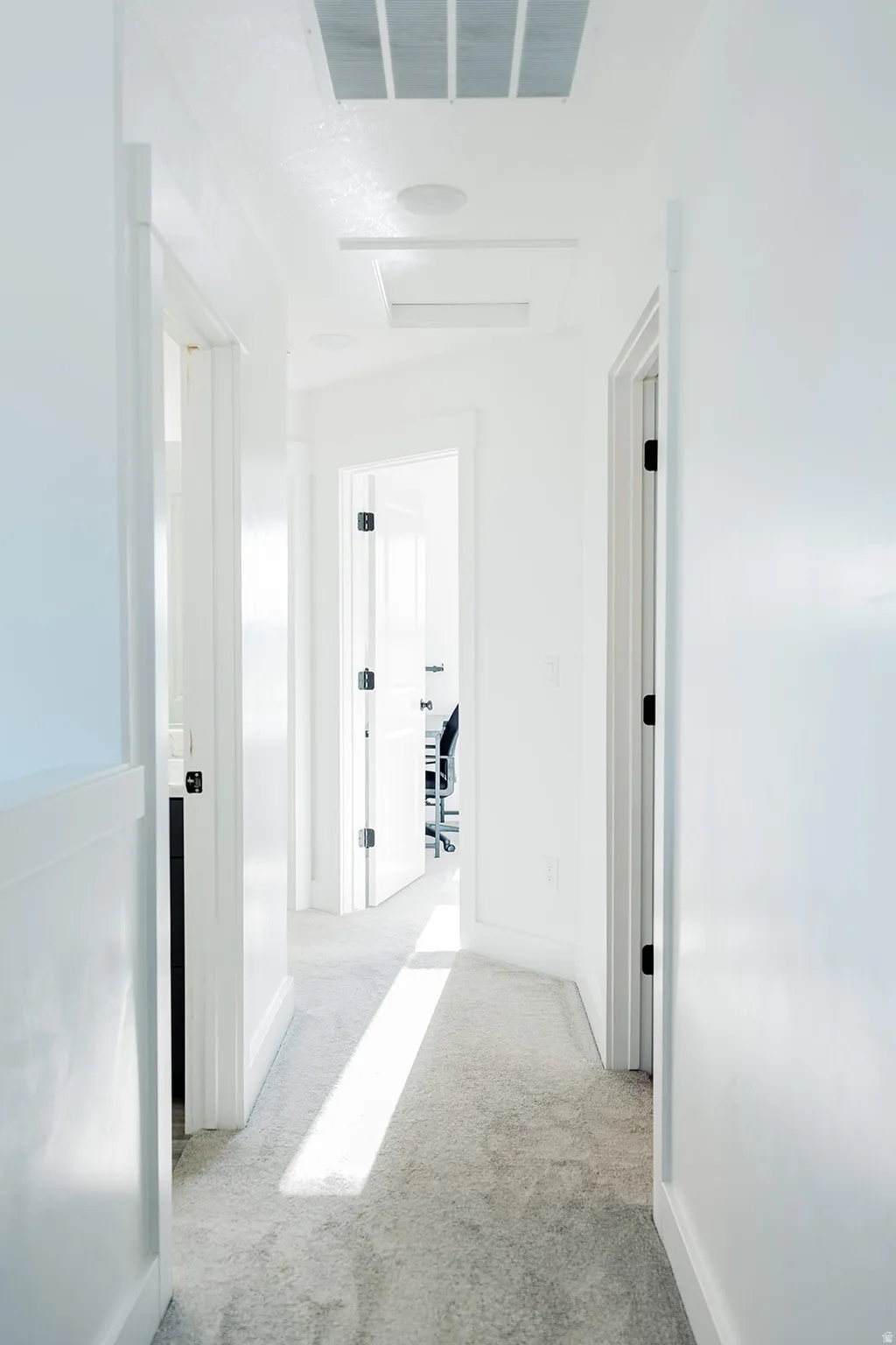 Hallway featuring light-colored carpeting, white walls, and white trim