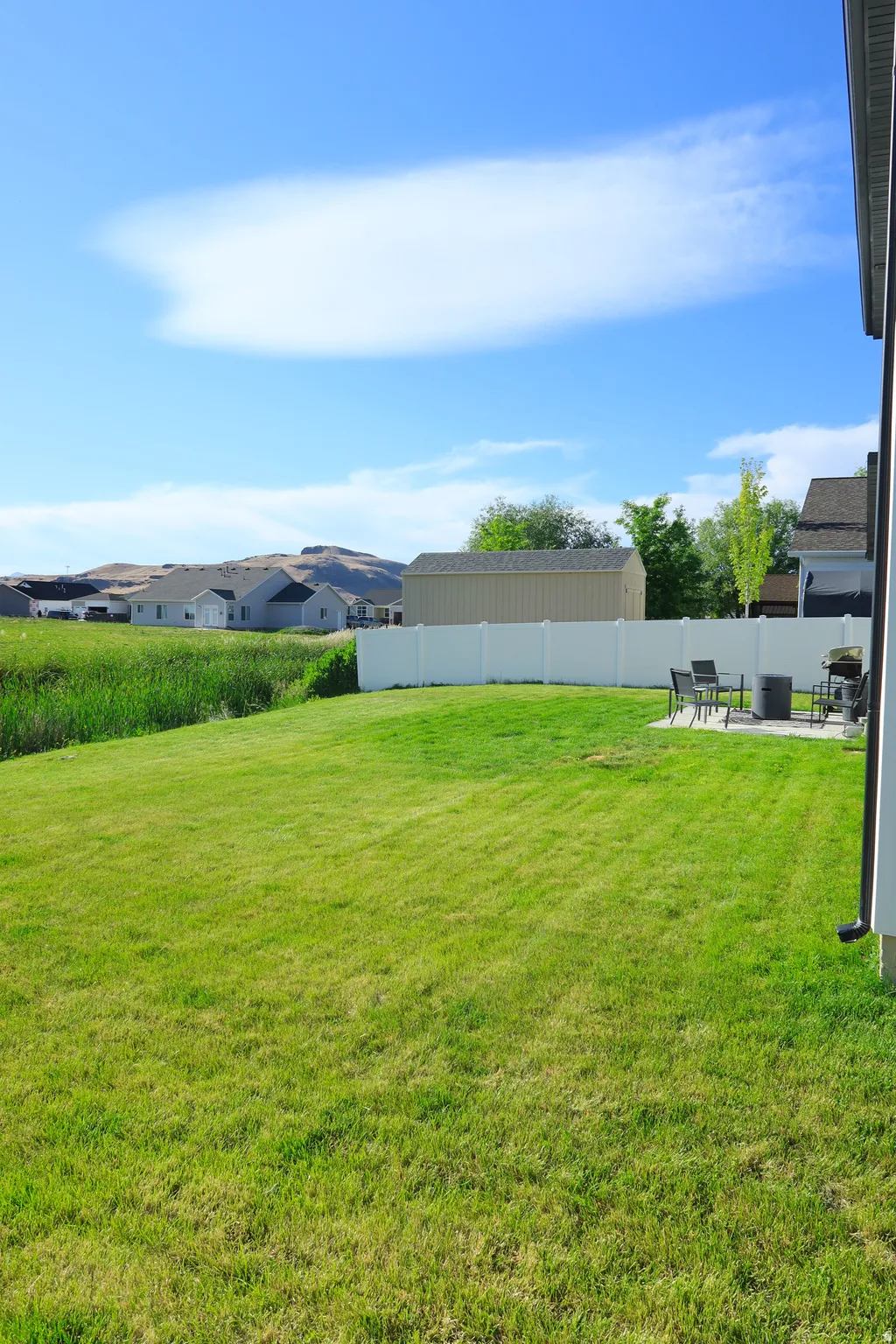 Expansive green lawn with a white privacy fence