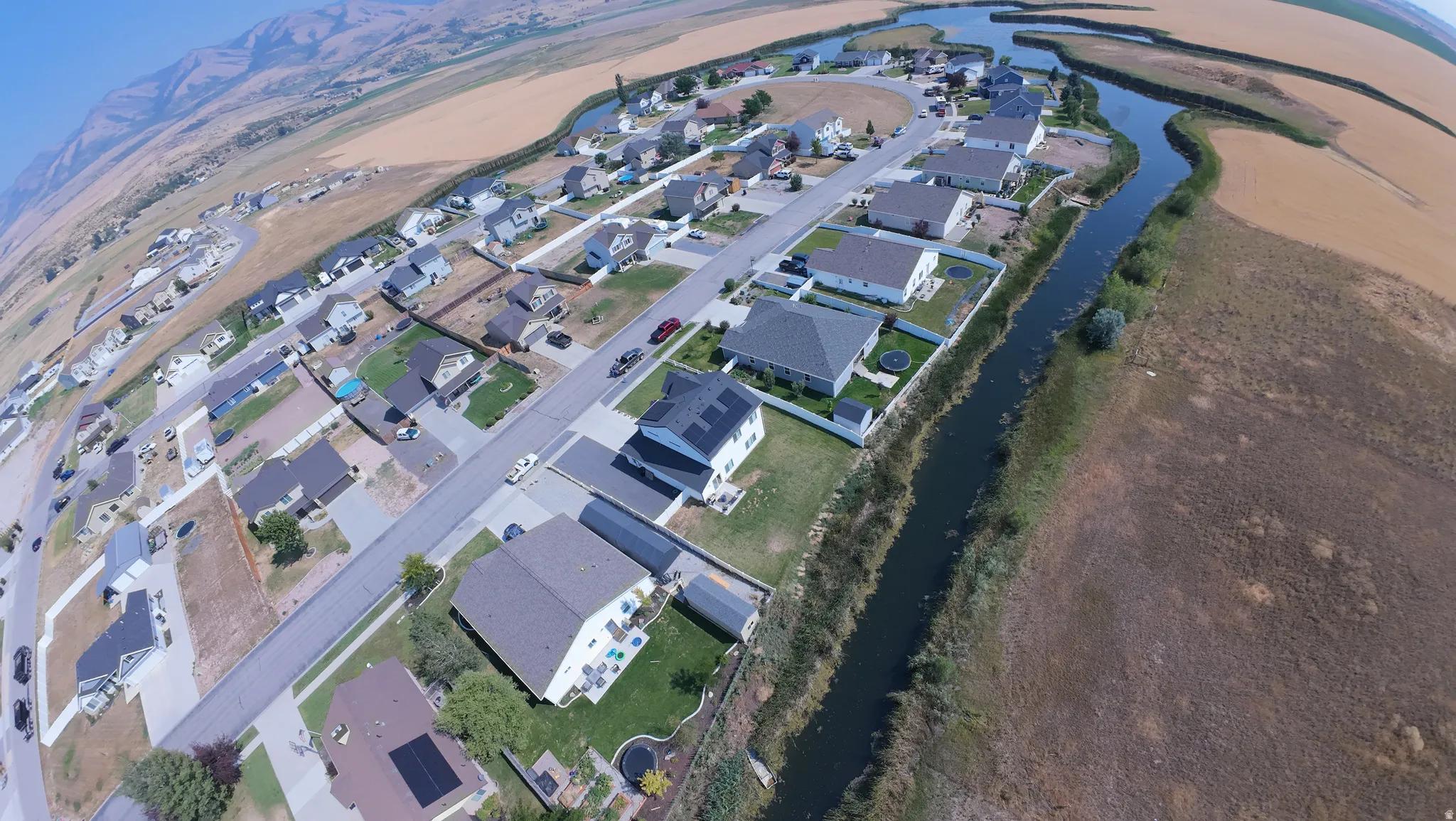 Aerial perspective showcasing residential properties, a winding waterway, and distant mountains