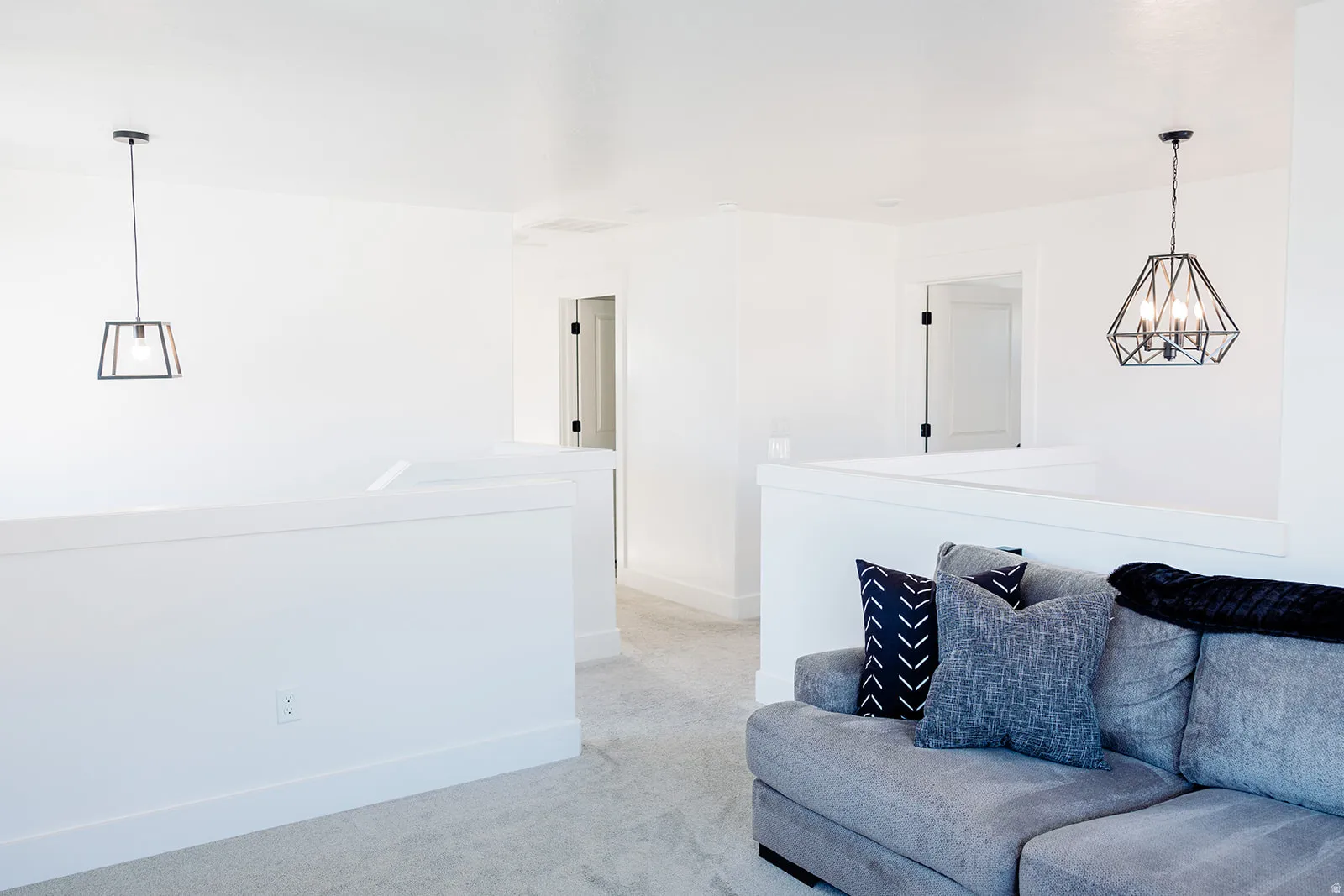 Loft area featuring neutral carpeting and two distinct geometric pendant light fixtures