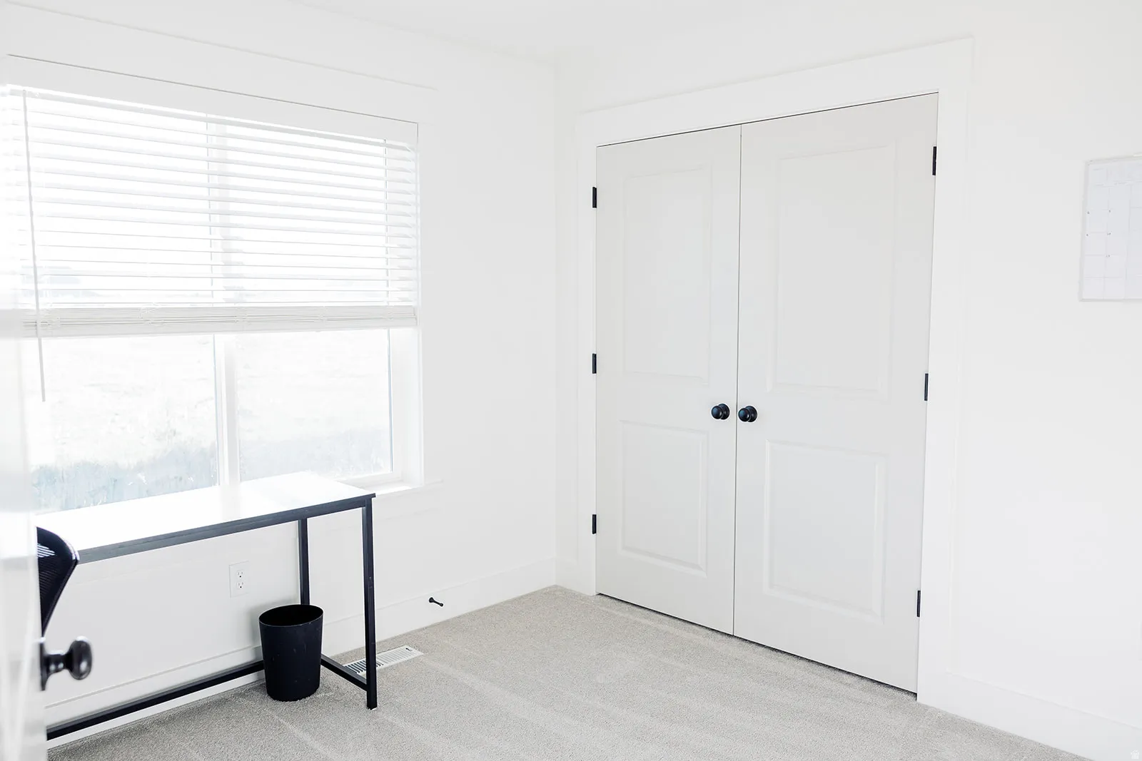 Bright room featuring a large window with horizontal blinds, providing abundant natural light