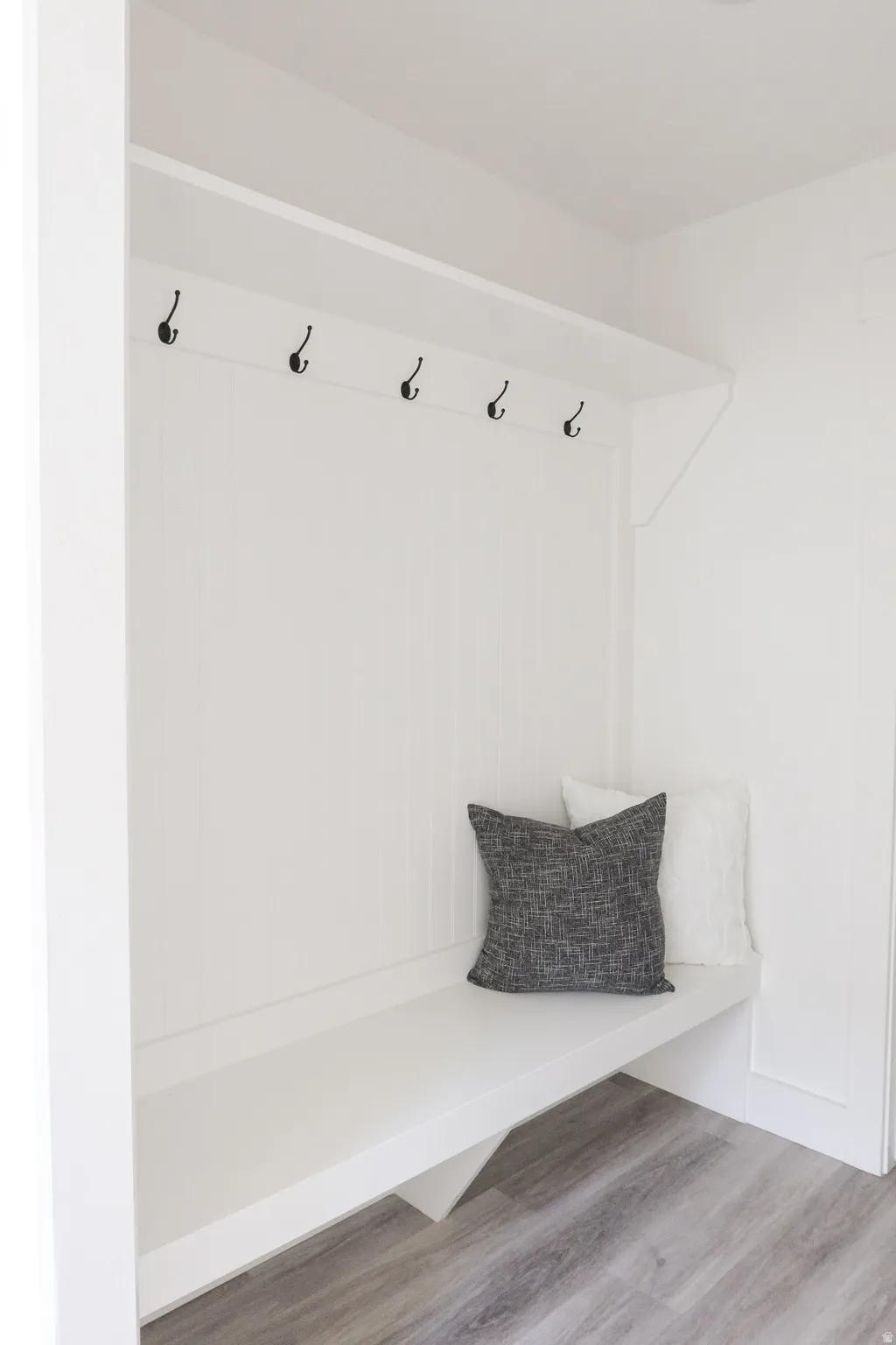 Built-in bench with beadboard backing, overhead shelf, and multiple coat hooks
