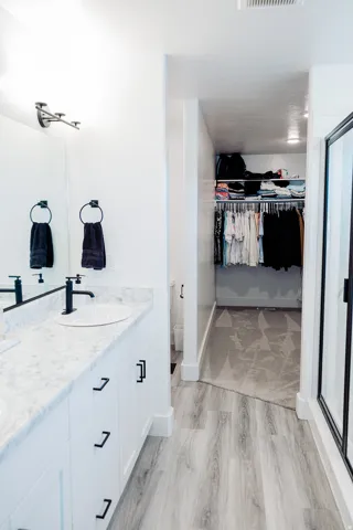 Bathroom vanity with dual undermount sinks, stone-finish countertop, and black hardware