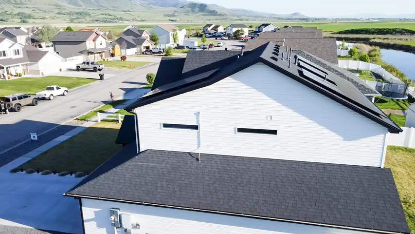 Contemporary siding exterior with a dark shingle roof and integrated solar panels facing East and West.