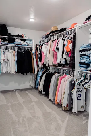 Spacious walk-in closet featuring wall-mounted shelving and ample hanging rods