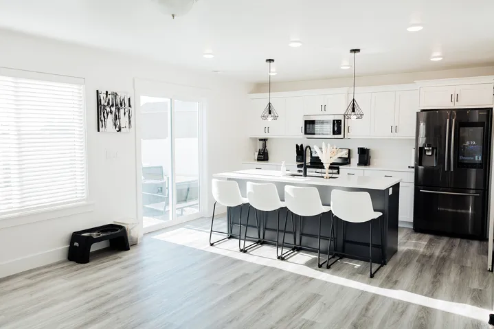 Kitchen featuring a dark-toned island with seating, white shaker-style cabinetry, and stainless steel appliances