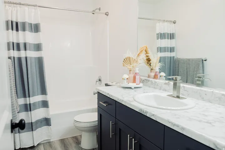 Bathroom featuring a vanity with a white countertop and undermount sink, dark cabinetry, and a chrome faucet