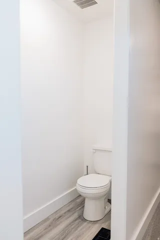 Master Bathroom featuring a single toilet, wood-finish flooring, white baseboards, a ceiling vent, and recessed lighting