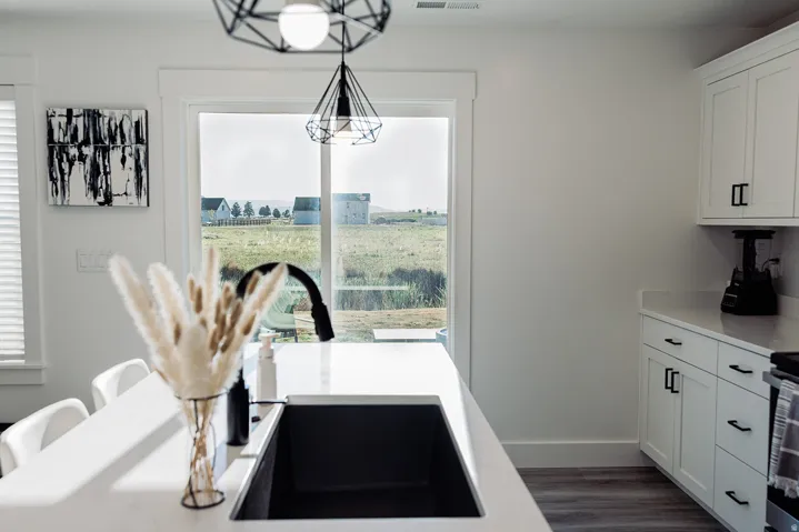 Kitchen featuring white cabinetry with black hardware, white countertops, and wood-finish flooring