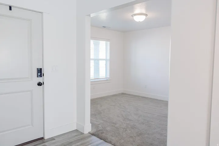 Entryway featuring a paneled door with matte black hardware, wood-finish flooring, and crisp white trim