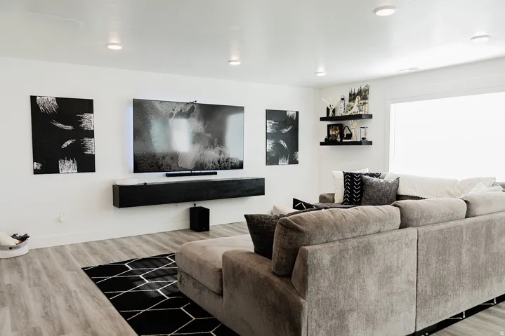 Spacious living area featuring light wood-finish flooring, recessed lighting, and a prominent built-in media console