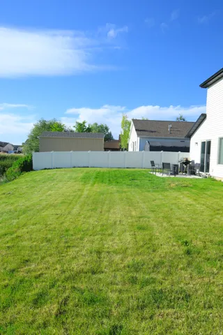 Expansive green lawn with a white privacy fence, complemented by a concrete patio for outdoor enjoyment