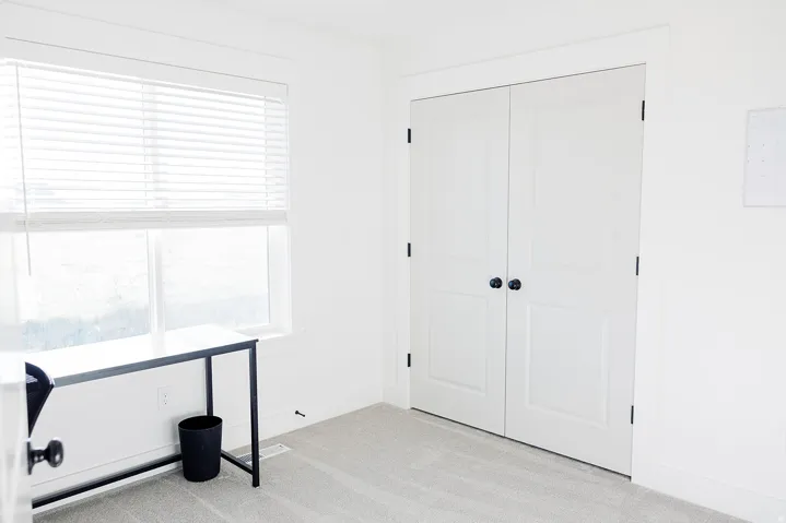 Bright room featuring a large window with horizontal blinds, providing abundant natural light
