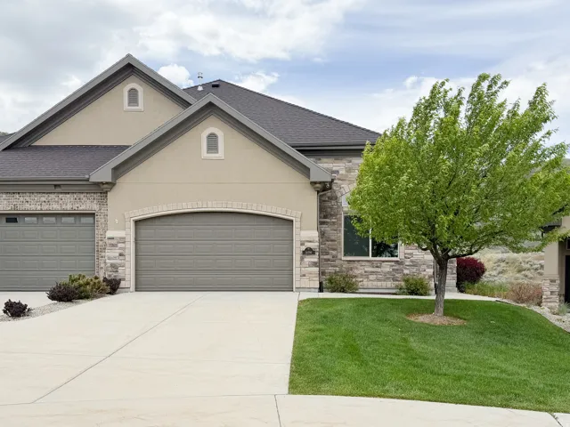 Stone and stucco exterior featuring a two-car garage with an additional single-car garage