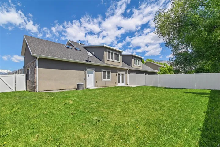 Expansive green lawn with a white vinyl fence enclosing the property
