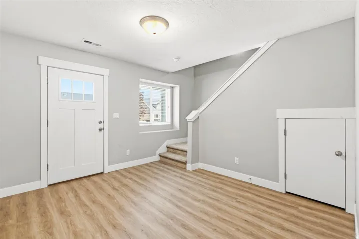 Entryway featuring wood-finish flooring, a white paneled door with window panes, and a flush mount ceiling light