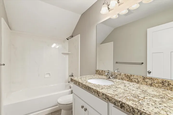 Bathroom vanity with a granite countertop, undermount sink, and chrome faucet