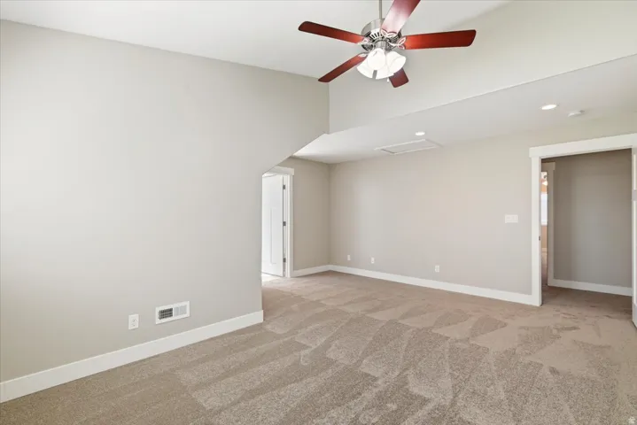 Spacious room featuring vaulted ceilings, light-toned walls, and patterned carpeting