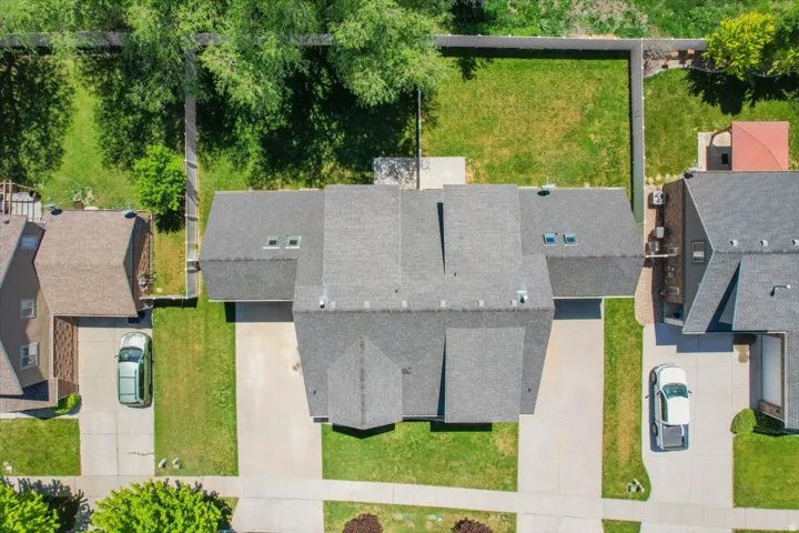 Overhead perspective showcasing a residential property with a dark shingled roof and multiple skylights