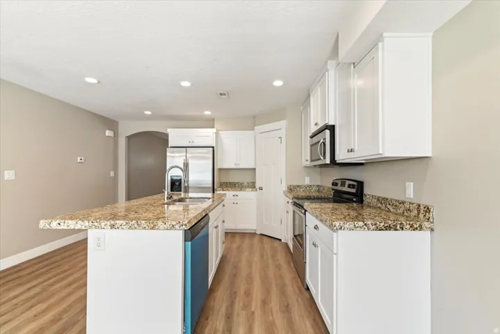 Kitchen featuring wood-finish flooring and white cabinetry