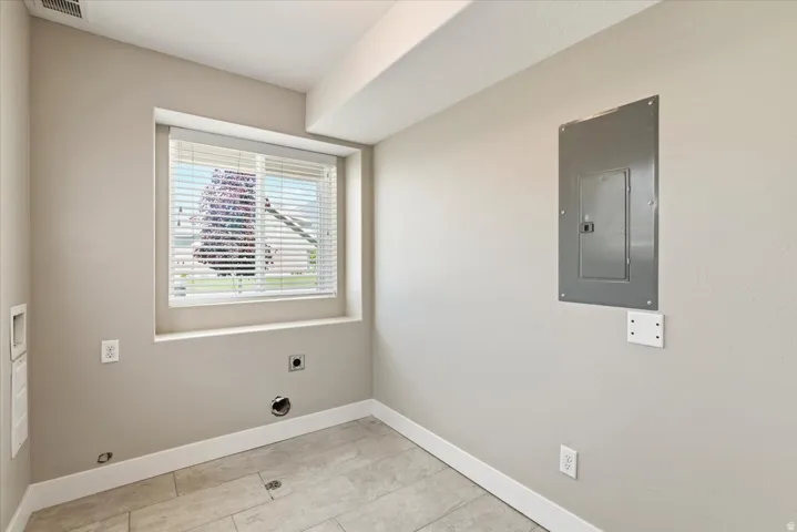 Utility room featuring light neutral wall paint, a window with horizontal blinds, and ceramic tile flooring