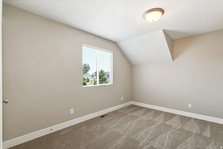 Carpeted room with a window featuring horizontal blinds