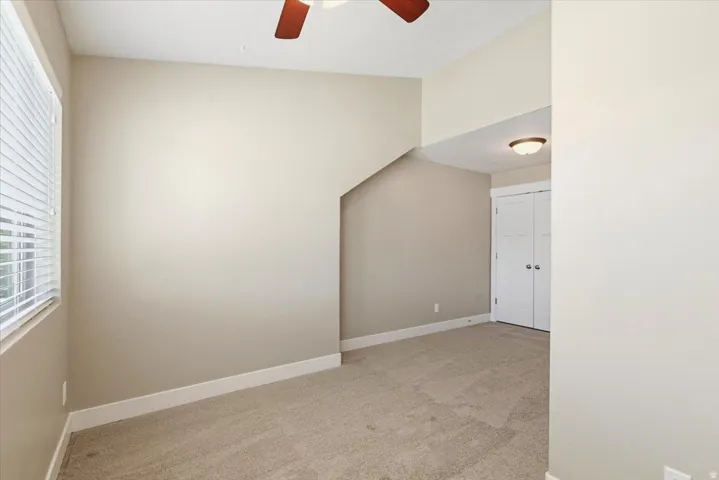 Carpeted room with a vaulted ceiling and a ceiling fan