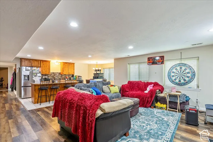 Spacious open-concept room featuring wood-finish flooring, recessed lighting, and a kitchen area with wood cabinetry