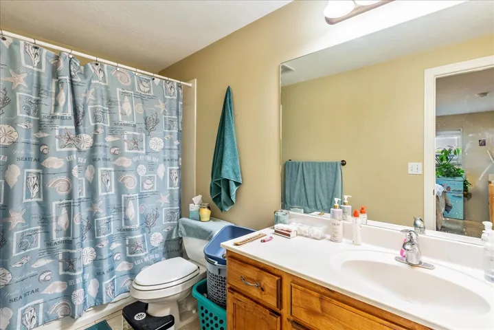 Full bathroom featuring a single vanity with wood cabinetry, a white countertop, and a chrome faucet