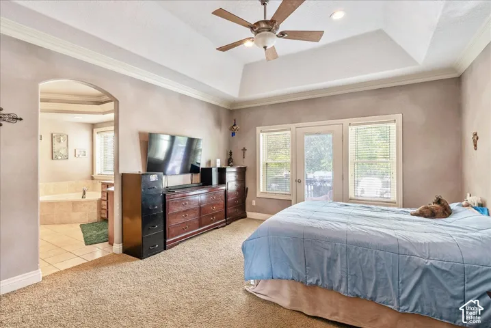 Spacious bedroom featuring vaulted ceilings, crown molding, a ceiling fan, and direct outdoor access