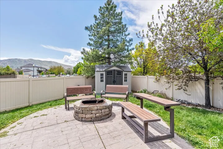 Stoned-paver patio area featuring a built-in stone fire pit, surrounded by benches and a matching picnic table
