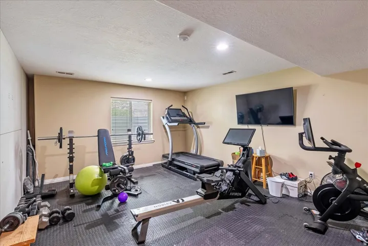 Dedicated fitness space featuring rubberized flooring, recessed lighting, and a single window with blinds