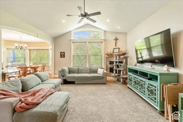 Vaulted ceiling with a ceiling fan, recessed lighting, and a stone fireplace