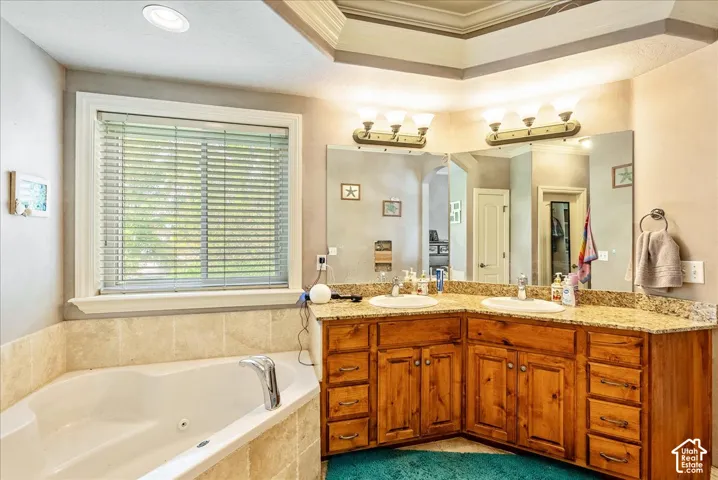 Corner jetted tub with tile surround, complemented by a dual vanity featuring wood cabinetry and a speckled countertop