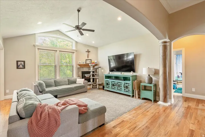 Spacious living area featuring vaulted ceilings, a ceiling fan, recessed lighting, and large windows with an arched transom