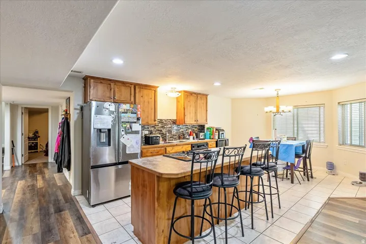 Kitchen featuring wood cabinetry, stainless steel refrigerator, and a mosaic tile backsplash