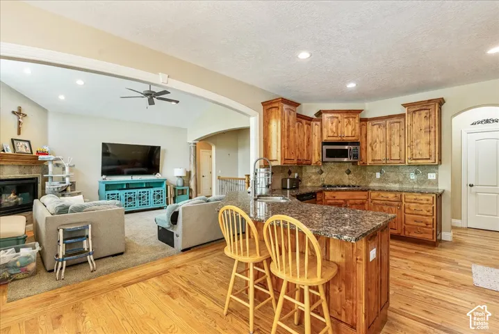 Open-concept kitchen featuring wood-finish flooring, a central island with a stone countertop, wood cabinetry, and recessed lighting