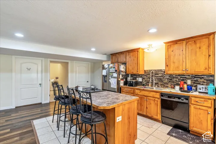 Kitchen featuring wood cabinetry, a mosaic tile backsplash, and a central island with bar seating