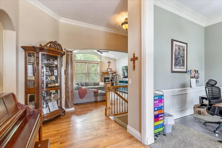 Expansive interior showcasing hardwood flooring, arched doorways, and crown molding
